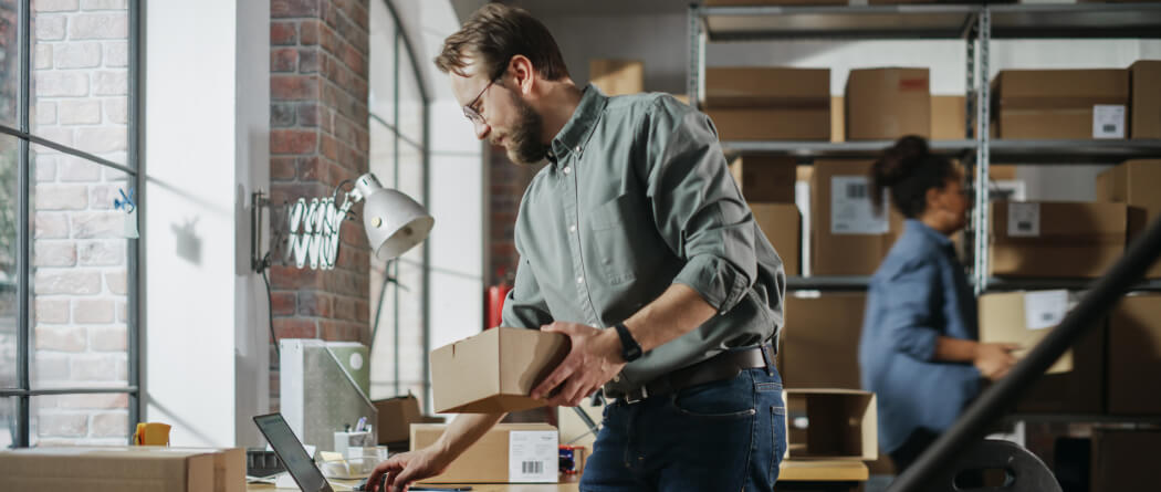 a man handling shipping boxes in a warehouse